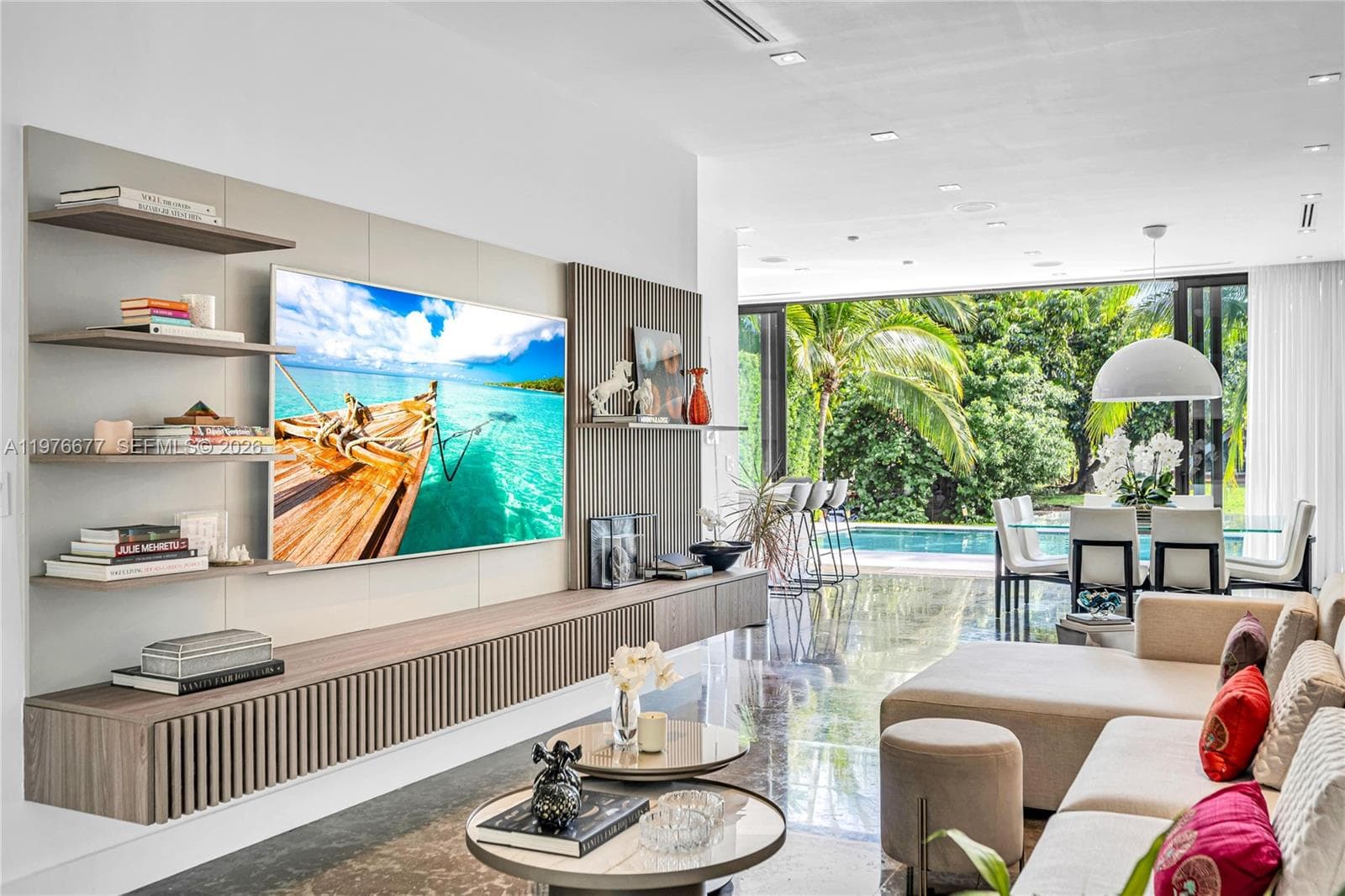 Custom wall-mounted media console with fluted wood-finish cabinetry, integrated open shelving, recessed ceiling lighting, polished stone flooring, and expansive multi-panel glass doors