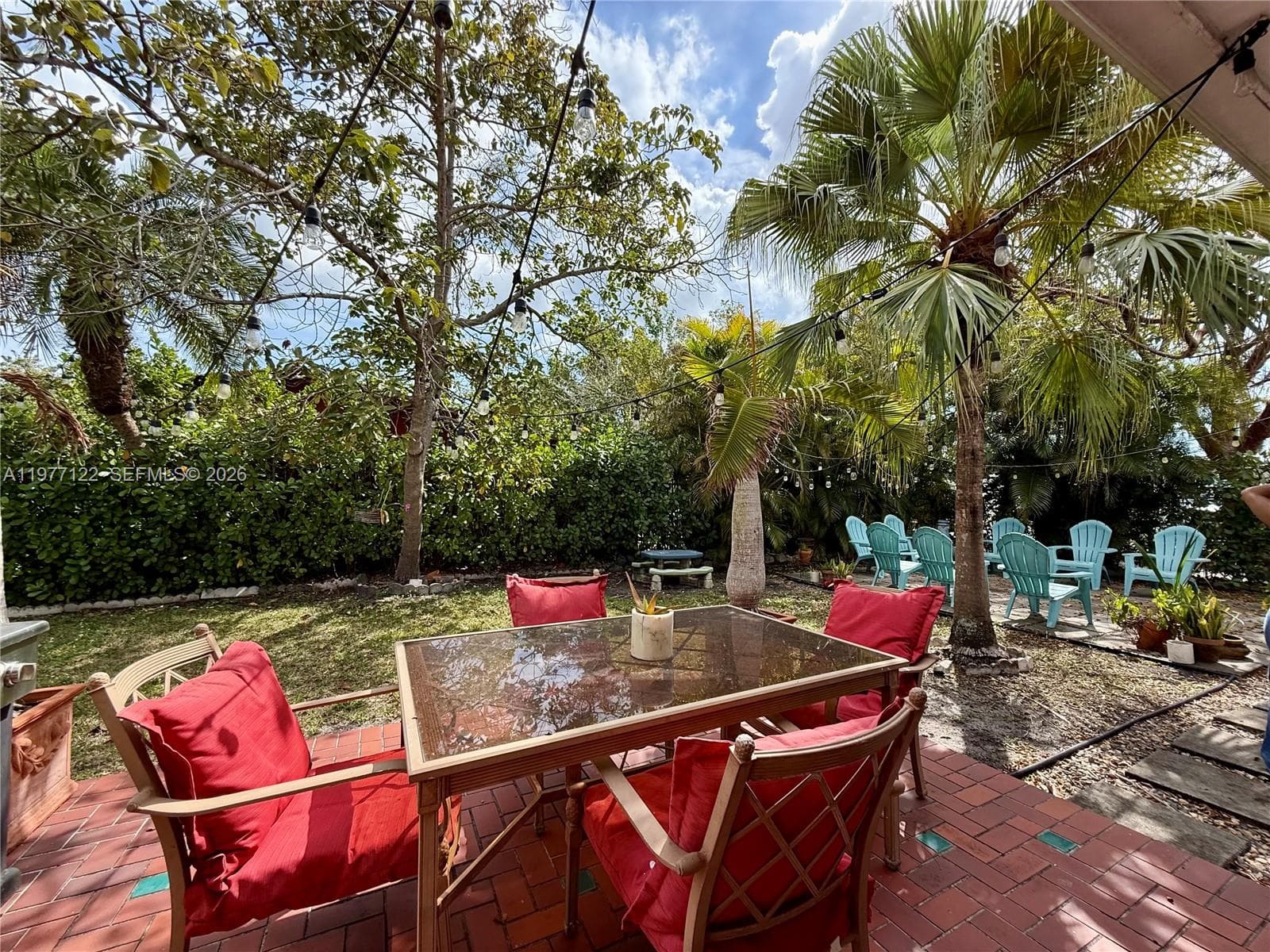 Large backyard with twinkly lights, gas grill, and patio furniture