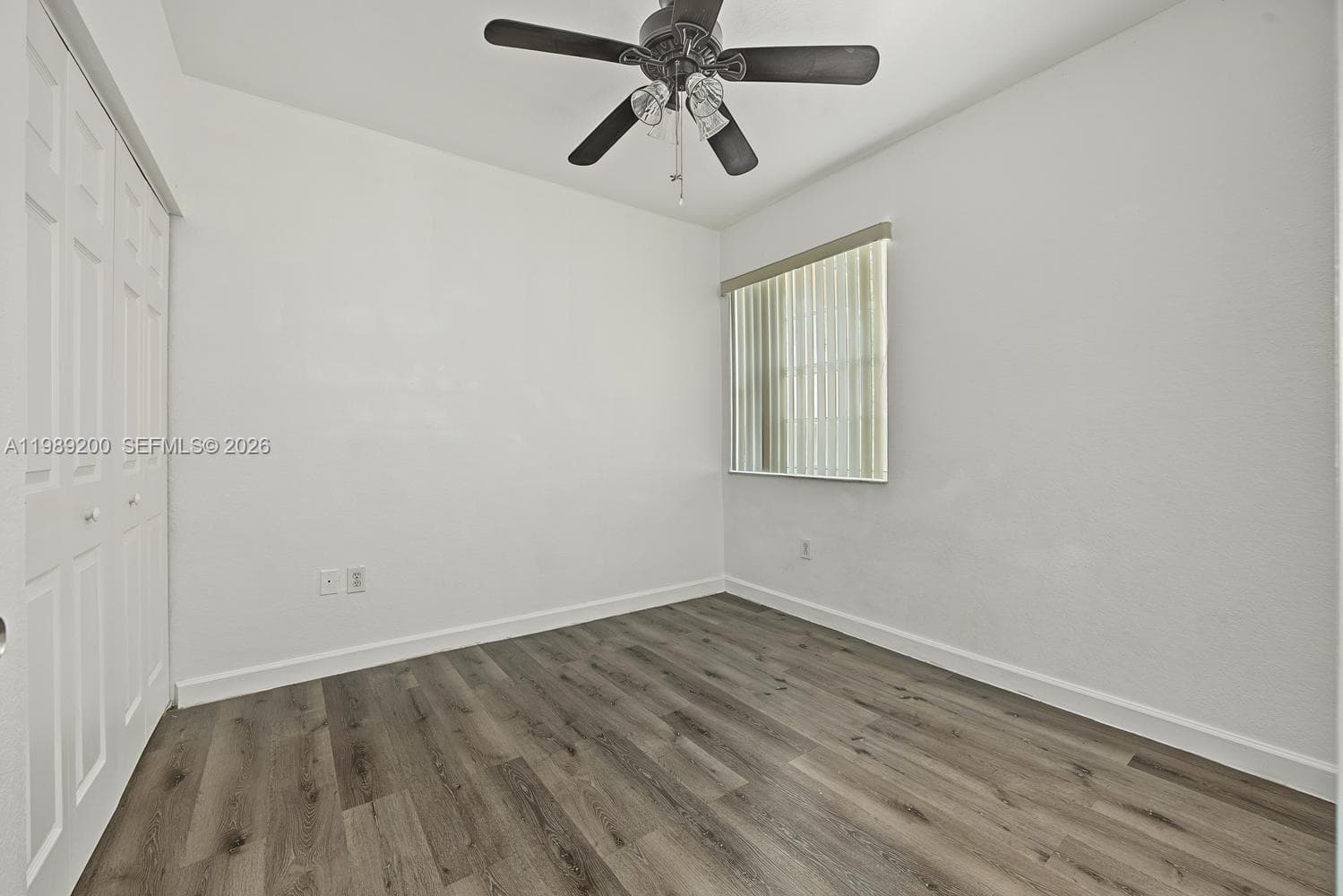 Room featuring wood-finish flooring, a ceiling fan with integrated lighting, and a closet with bifold doors