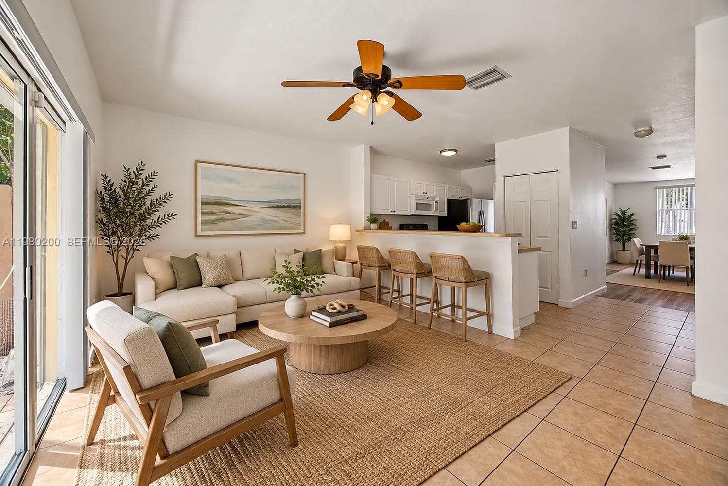 Ceramic tile flooring, ceiling fan with integrated lighting, kitchen breakfast bar, and sliding glass door