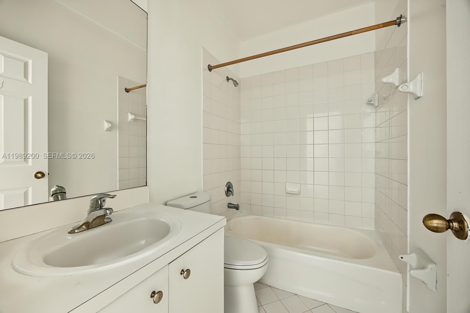 Full bathroom featuring a white vanity with an integrated basin, a large wall-mounted mirror, a tub-shower combination with ceramic tile surround, and tile flooring
