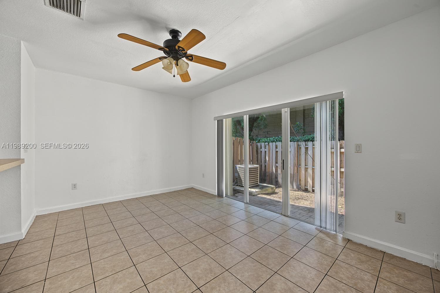 Interior space featuring ceramic tile flooring, a ceiling fan with integrated lighting, and a sliding glass door opening to a paved patio area