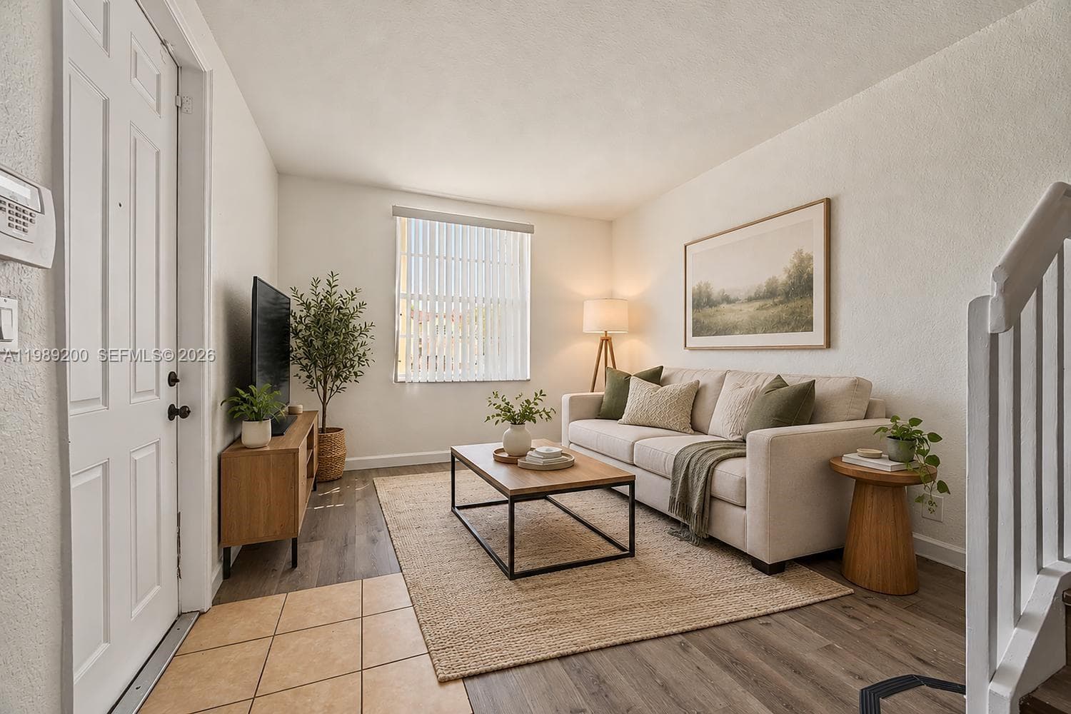 Wood-finish flooring, neutral walls, vertical window blinds, and a tiled entryway