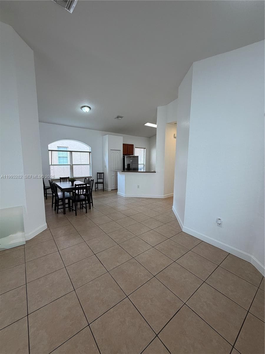 This is a photo that shows the dining area and kichen. The foreground shows thespace between the front door and dining room/kitchen area.
