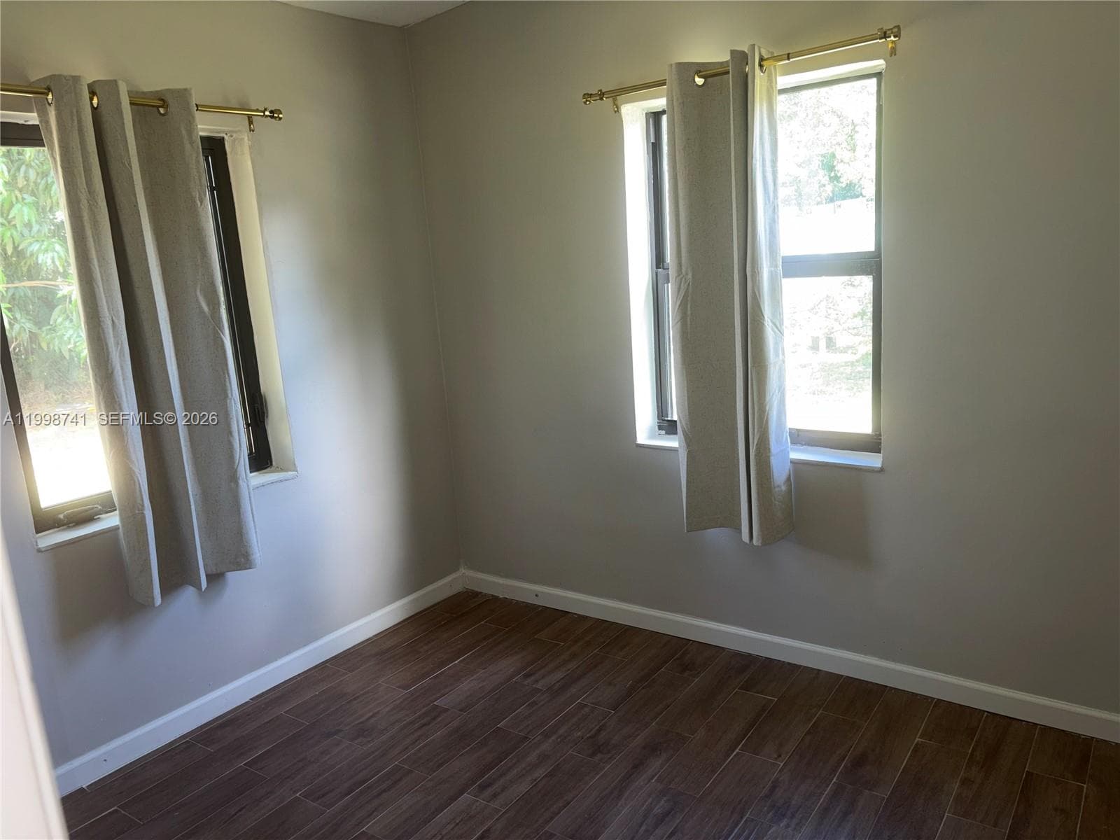 Room featuring wood-finish tile flooring and dual windows with mounted hardware