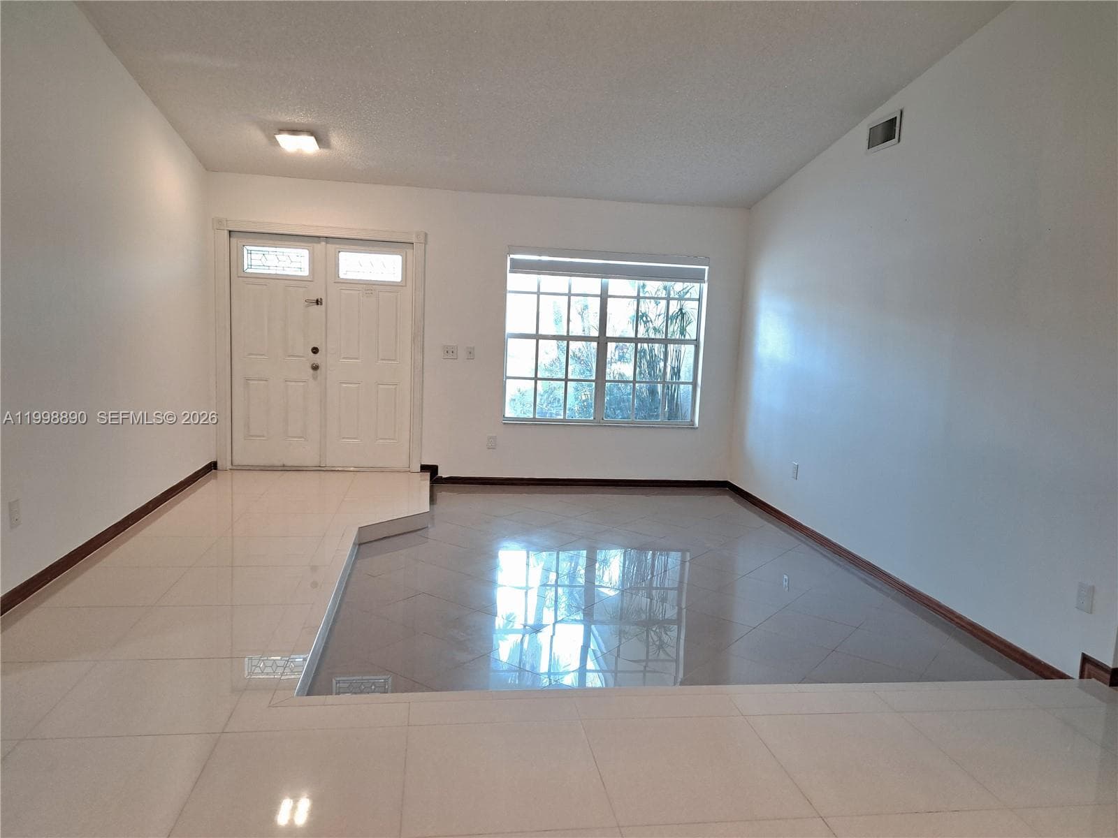 Open-concept space featuring vaulted ceilings, polished tile flooring, a sunken floor level, and a double-door entryway
