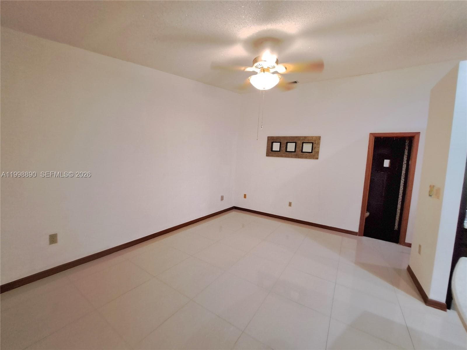 Interior space featuring light-toned tile flooring, neutral wall paint, and a ceiling fan with integrated lighting