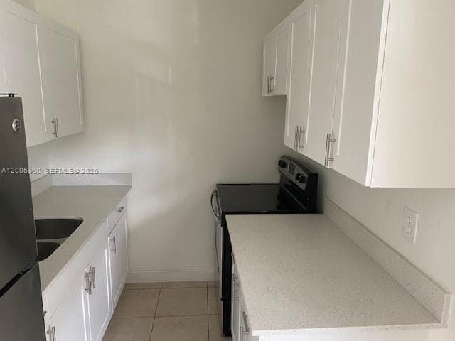 Kitchen featuring white shaker-style cabinetry, solid-surface countertops, dual-basin stainless steel sink, and tile flooring