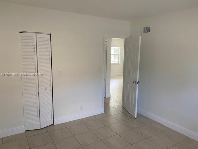 Interior space featuring neutral wall paint, tile flooring, louvered bi-fold closet doors, and a paneled interior door