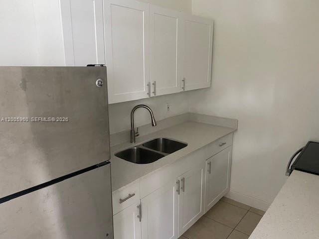 Kitchen featuring white shaker-style cabinetry, neutral solid-surface countertops, a stainless steel double-basin sink with a gooseneck faucet, and stainless steel appliances