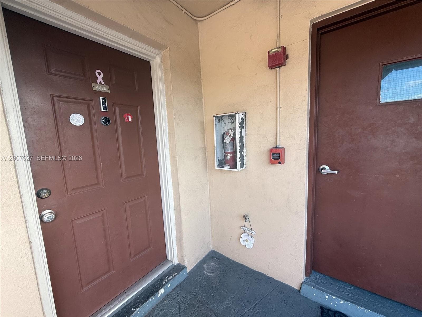 Two exterior entry doors featuring dark-toned solid panels, metal hardware, and a built-in recessed fire extinguisher cabinet