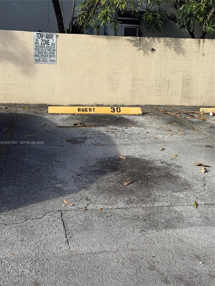 Designated guest parking space with a concrete wheel stop and asphalt surface