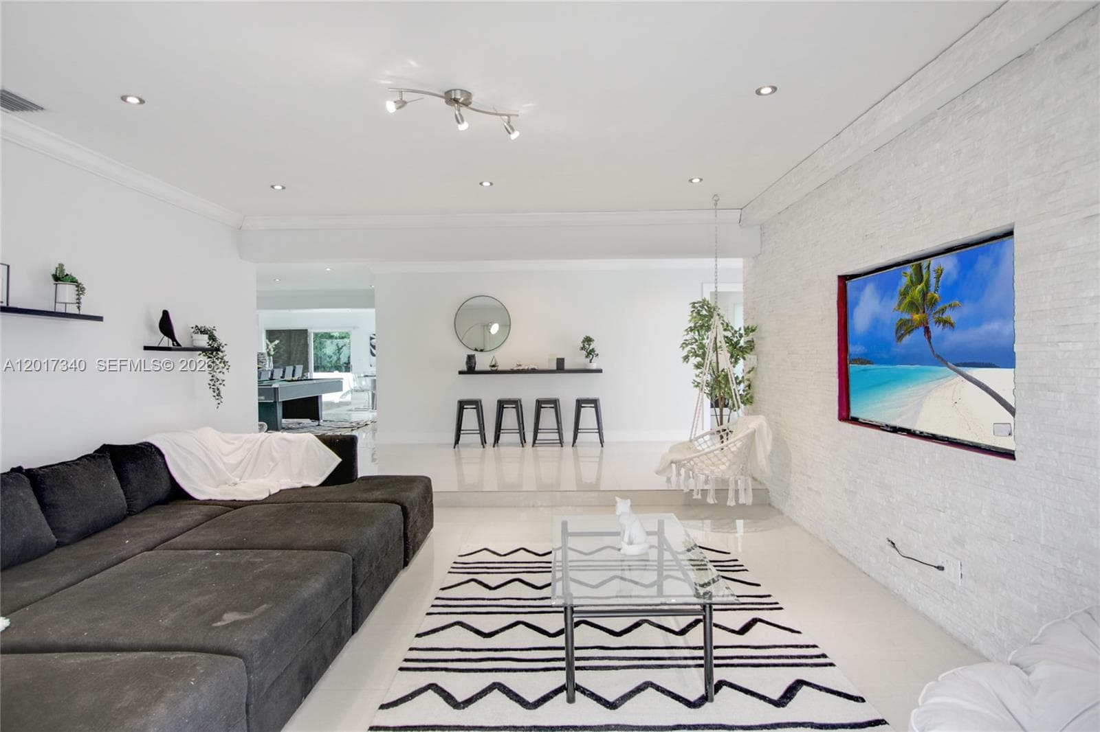 Living area featuring a floor-to-ceiling textured stone accent wall, recessed lighting, polished tile flooring, and a built-in wall-mounted display ledge