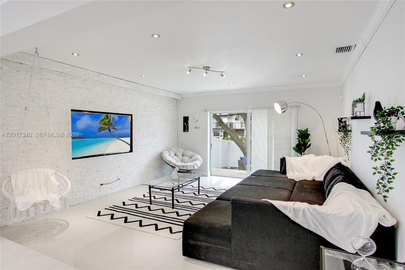 Living area featuring a textured masonry accent wall, large-format tile flooring, recessed lighting, and sliding glass door access to the exterior