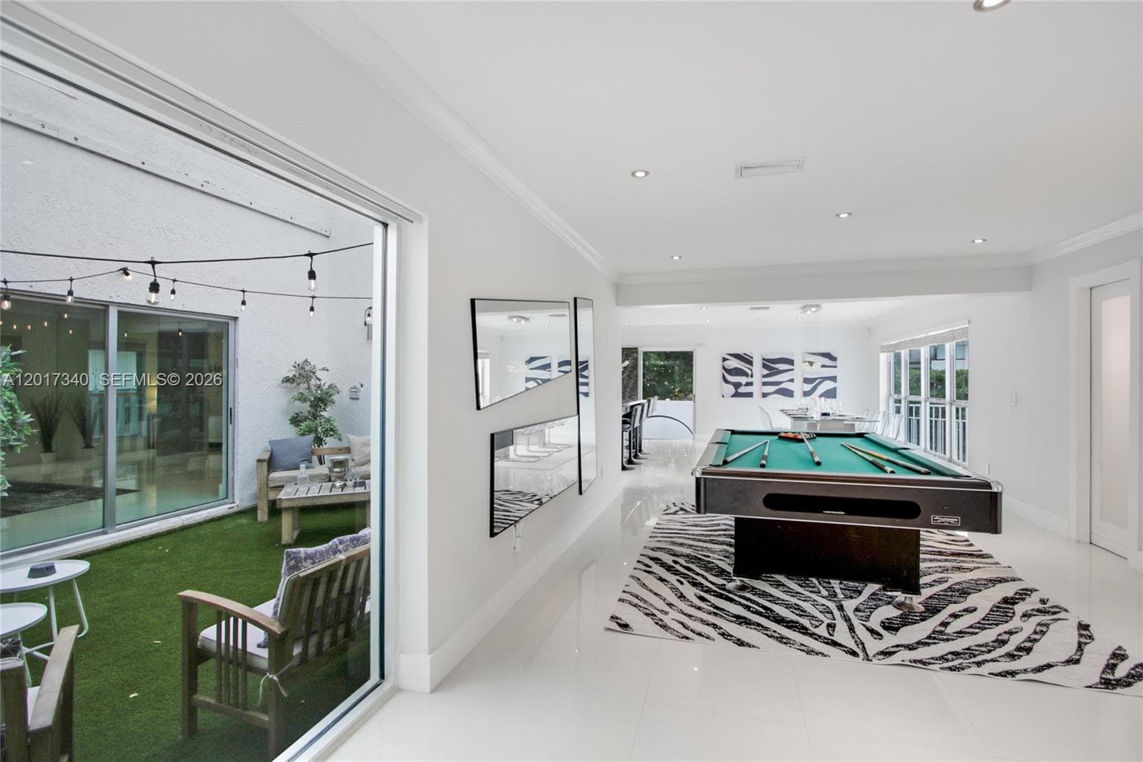 Open-concept interior featuring large-format polished tile flooring, recessed lighting, and a floor-to-ceiling glass sliding door system