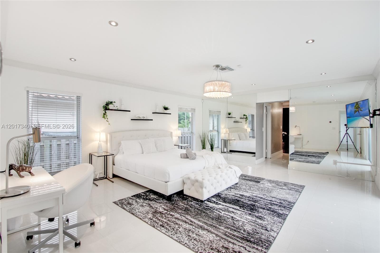 Spacious room featuring polished tile flooring, recessed lighting, a modern drum pendant light, wall-to-wall mirrored panels, and built-in floating wall shelves