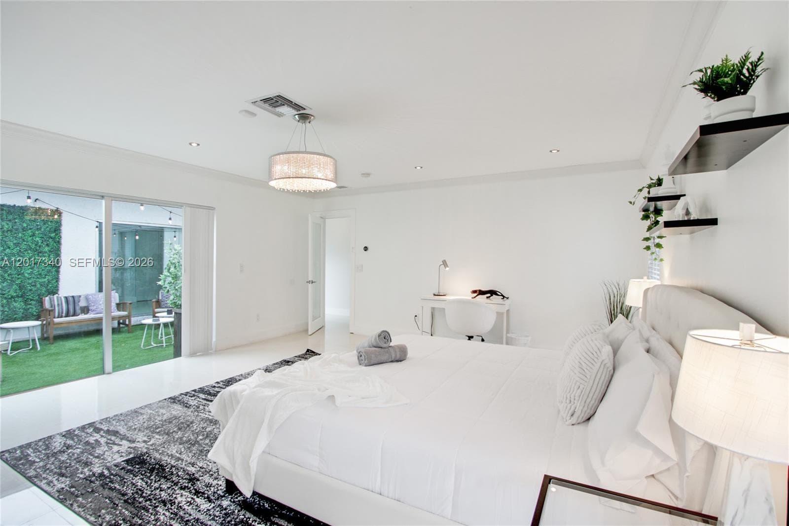 Bright interior space featuring polished tile flooring, recessed lighting, a drum-style pendant light fixture, built-in wall shelving, and large sliding glass doors