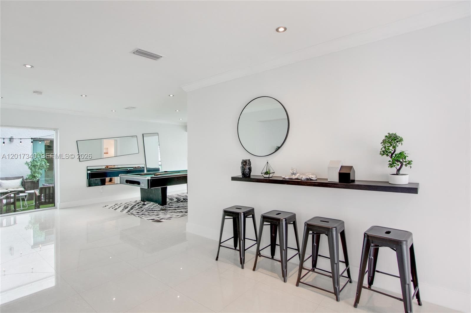 Open-concept interior featuring large-format tile flooring, recessed lighting, and a dark wood-finish wall-mounted ledge