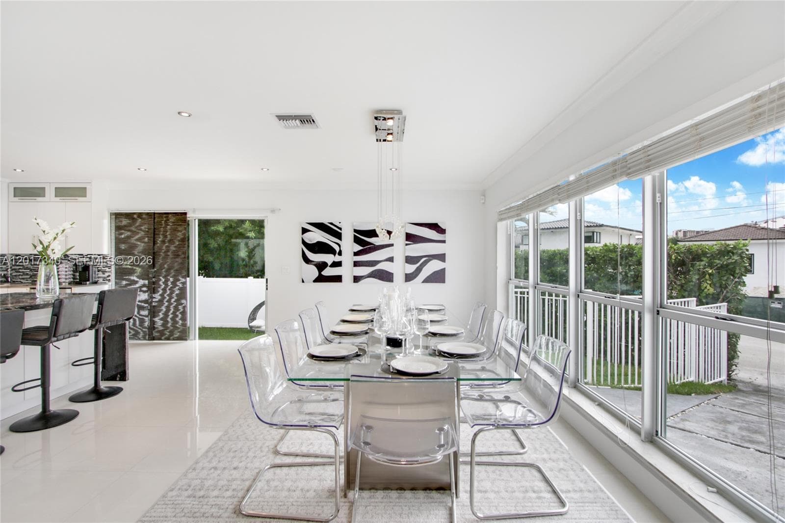 Open-concept dining area featuring large-format tile flooring, recessed ceiling lighting, a tiered chandelier, and extensive floor-to-ceiling windows