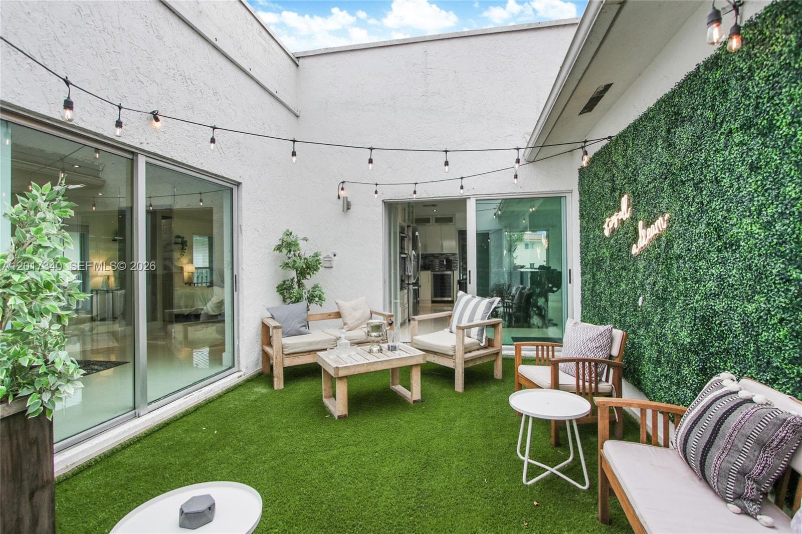 Enclosed courtyard featuring sliding glass doors, synthetic turf, and a green-wall accent feature