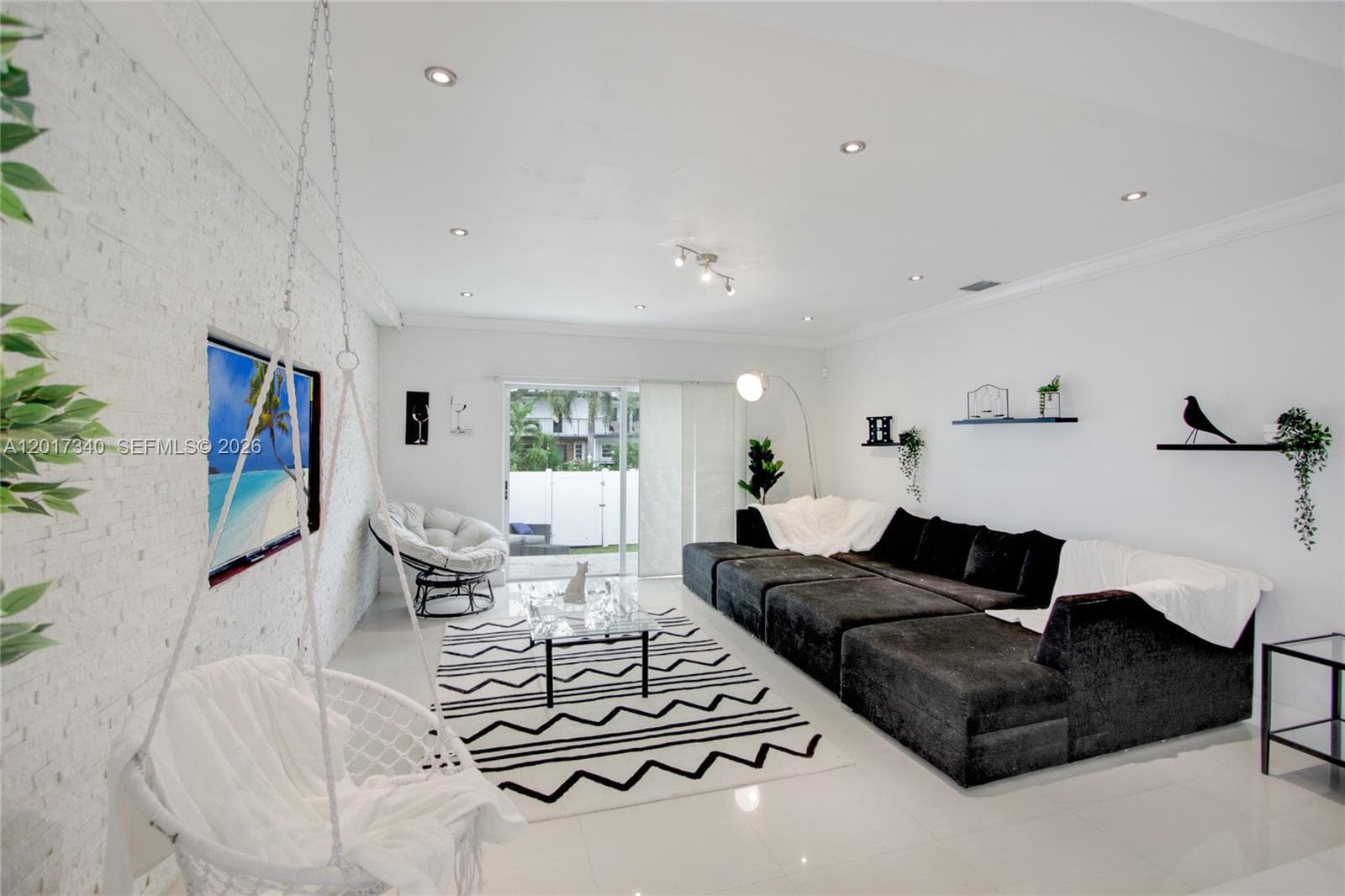 Living area featuring a white brick accent wall, polished tile flooring, recessed ceiling lighting, and sliding glass doors