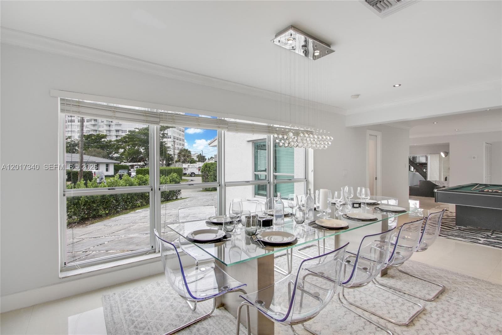 Dining area featuring large-format horizontal windows, modern crystal-style rectangular chandelier, and neutral tile flooring