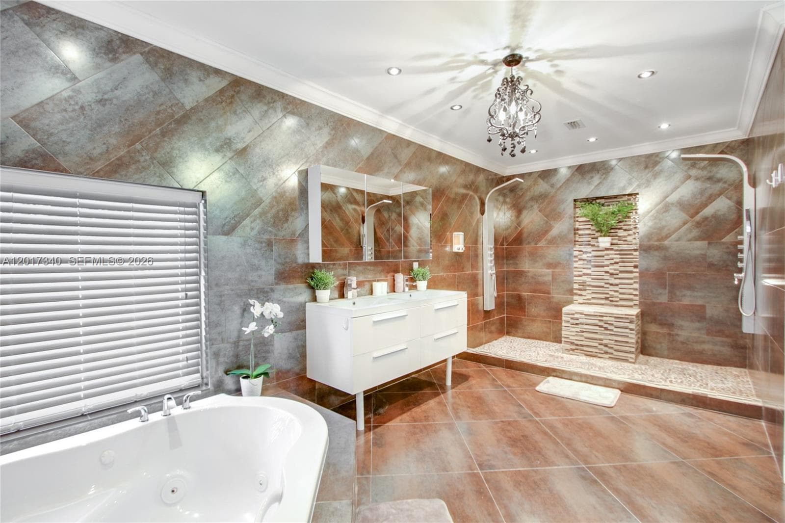 Bathroom featuring large-format diagonal wall and floor tile, dual-sink floating vanity, jetted soaking tub, and a walk-in shower with stone mosaic tile accents