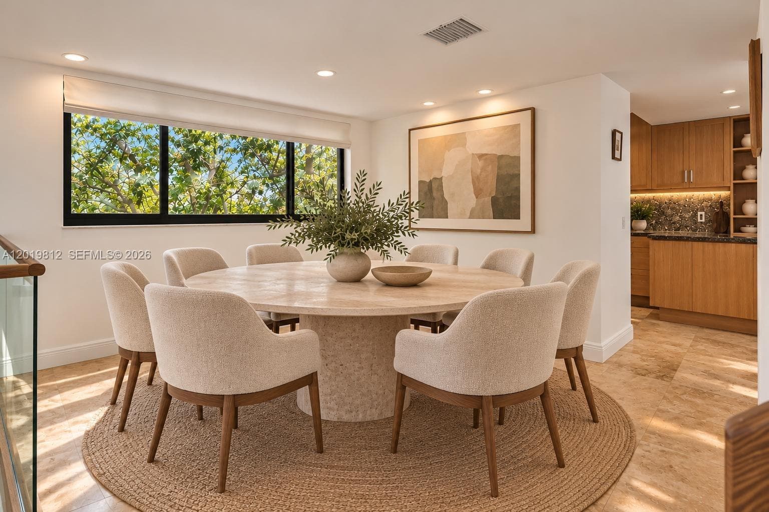 Natural stone tile flooring, large-format black-trimmed horizontal window, recessed ceiling lighting, and built-in wood-finish cabinetry