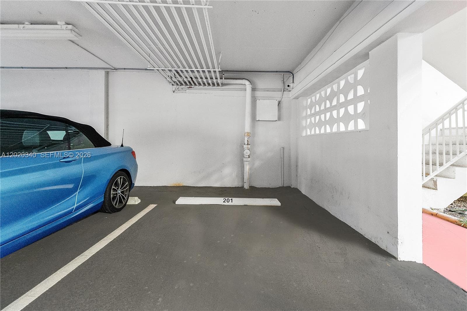 A covered assigned parking spot (#201) in a secure garage, with a decorative breeze-block wall — a classic mid-century Florida building detail.
