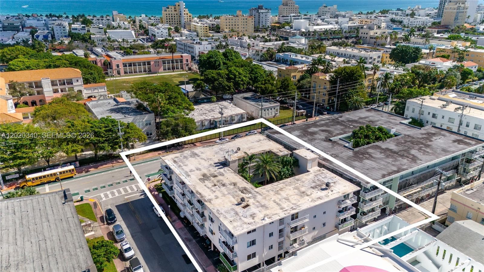 Aerial view showing the building just blocks from the ocean — the turquoise Atlantic is clearly visible in the background, with South Beach's Art Deco neighborhood and lush tree canopy surrounding it. An unbeatable location.