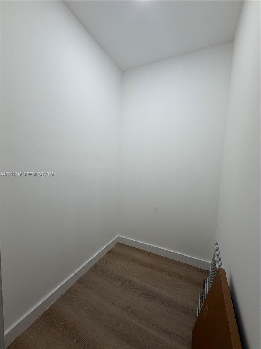 Enclosed space featuring neutral white wall finishes and wood-finish flooring