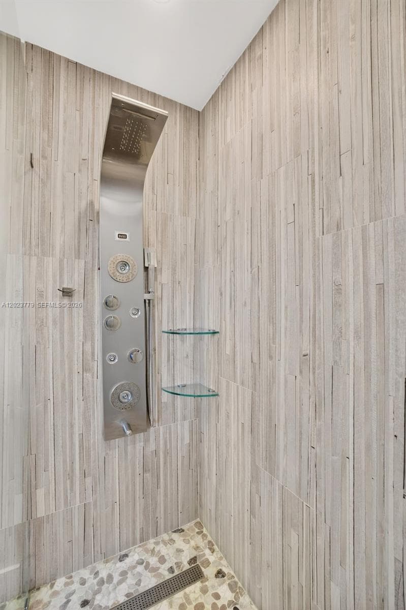 Primary bathroom w/ frameless glass enclosure, river rock look tile, multi function shower head, floor to ceiling wood look plank tile, medicine cabinet and upgraded vanity and flooring