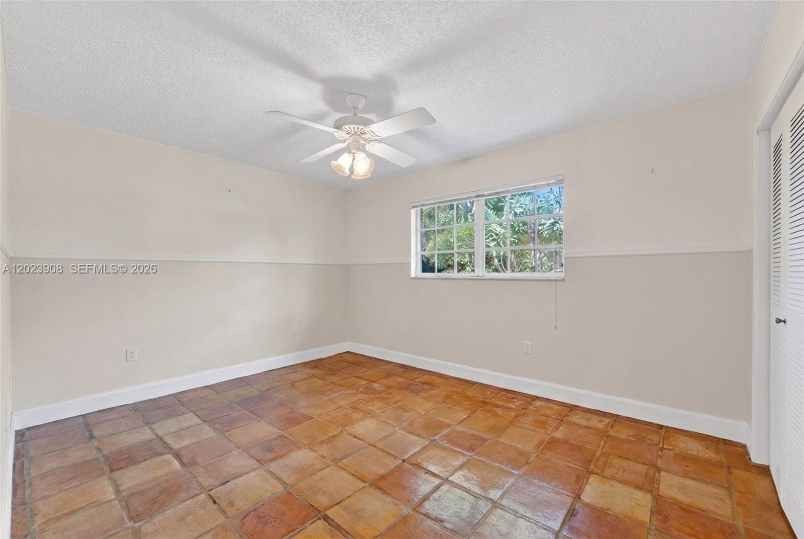 Room featuring square tile flooring, two-tone wall paint with chair rail molding, a multi-pane window, and a ceiling-mounted fan with integrated lighting