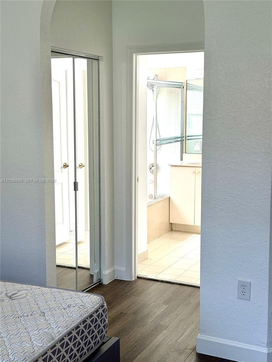 Looking into hallway to primary bathroom that has closets on both sides.