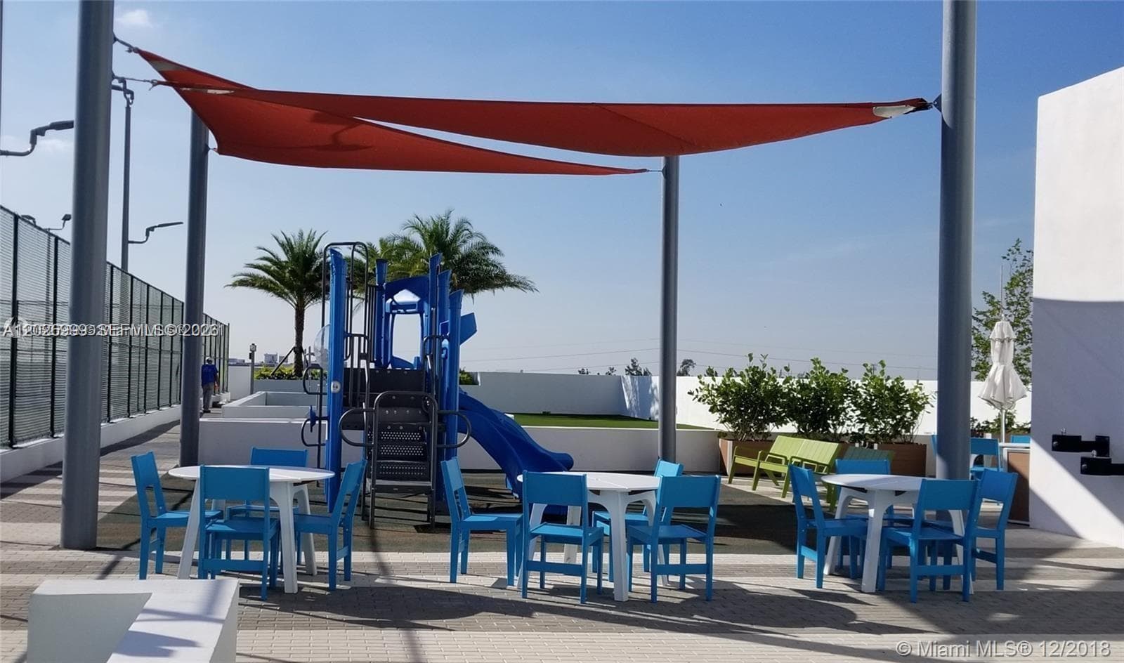 Elevated amenity level featuring tennis courts, open green spaces, and shaded lounge areas for entertainment and recreation.