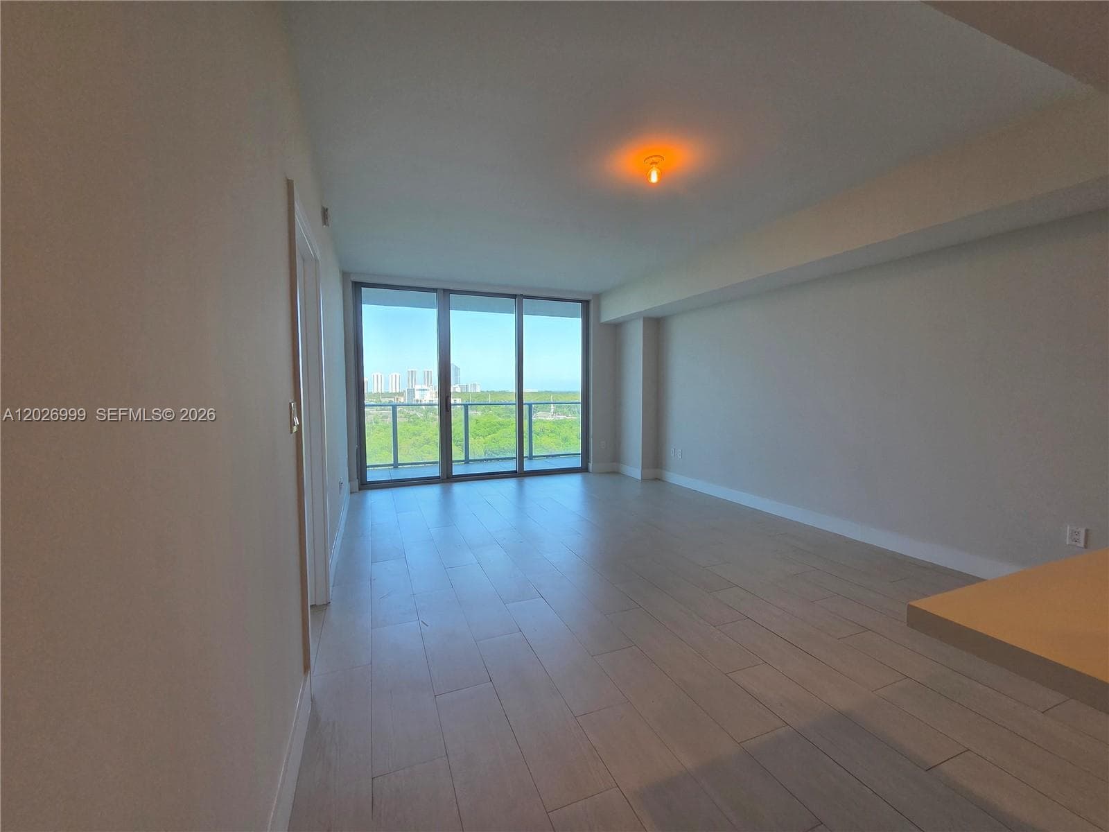 This open-concept layout connects the kitchen, dining, and living areas with light tile flooring and a natural flow toward the balcony.