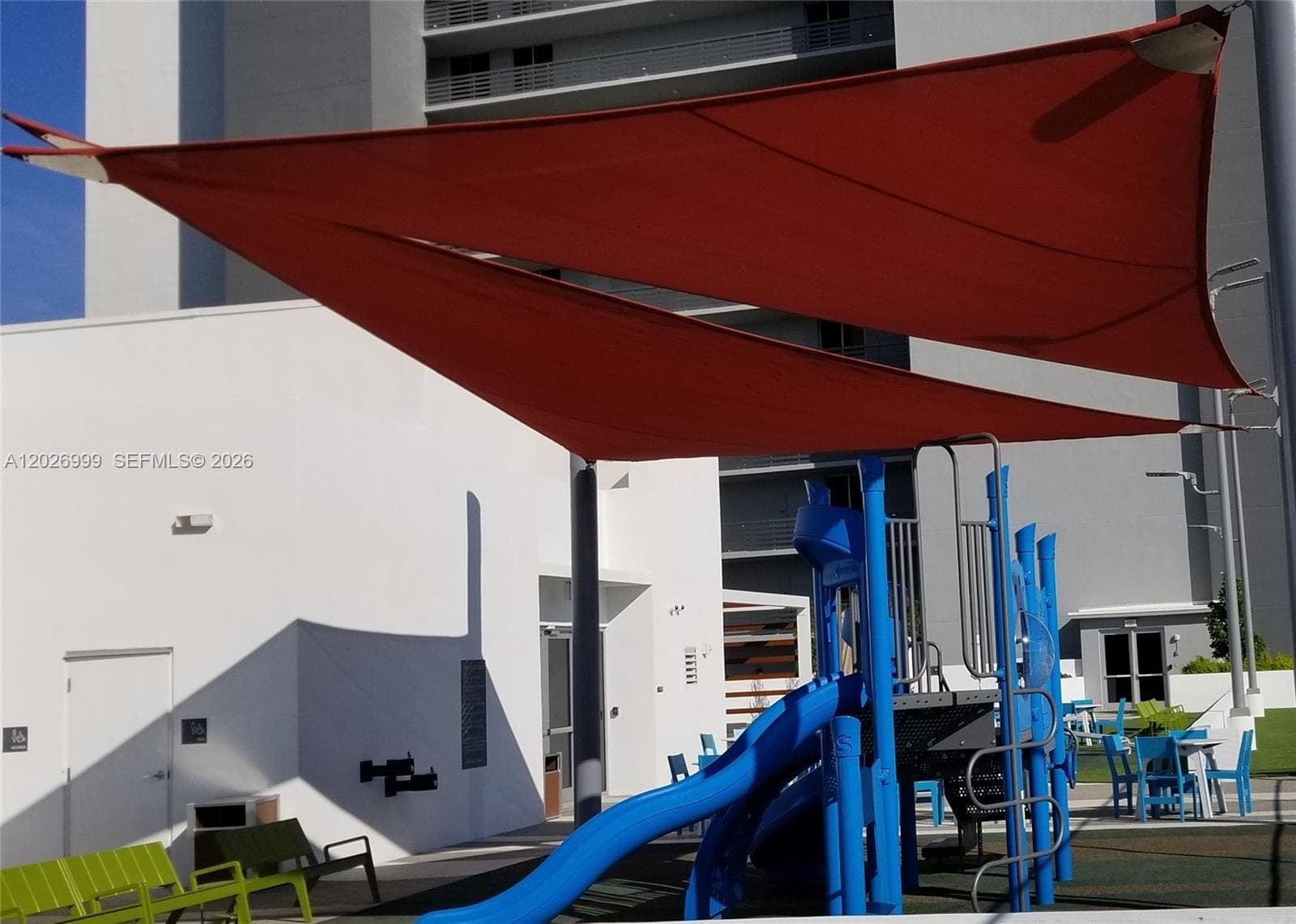 The outdoor pool deck features palm trees, lounge seating, and open sun areas framed by the surrounding landscape. The waterfront setting adds a relaxed resort-style atmosphere.