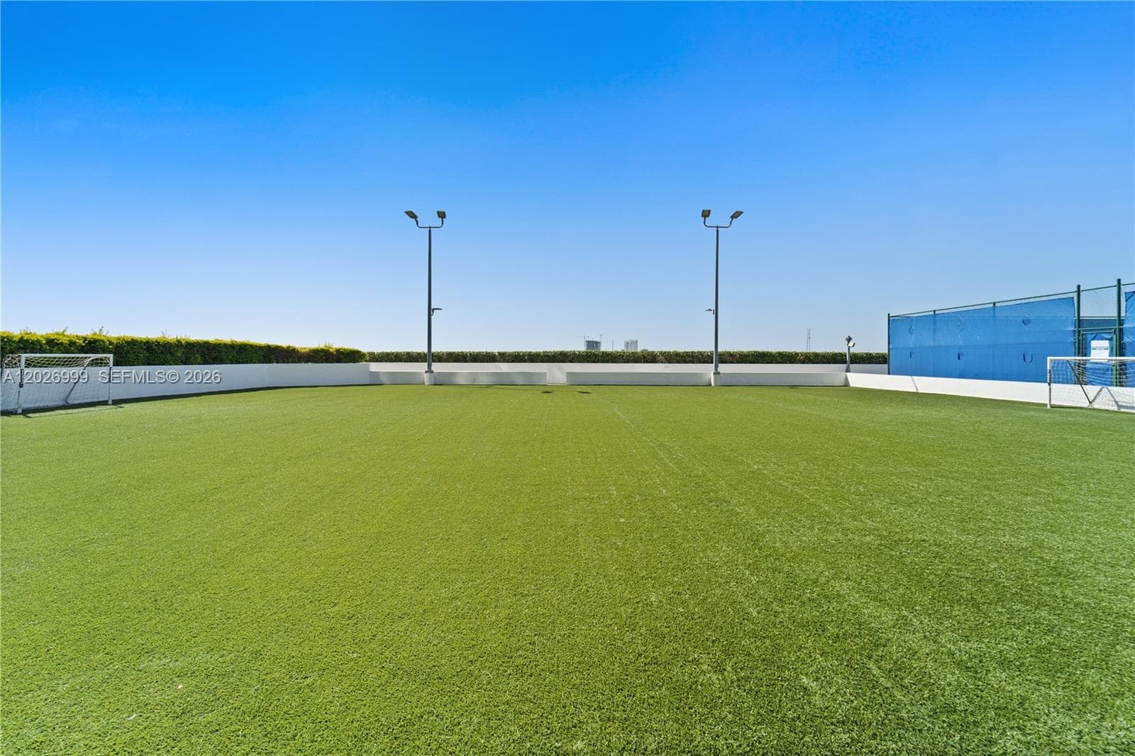 A well-maintained tennis court adds to the building’s active lifestyle amenities, complete with surrounding fencing and nearby outdoor seating areas.
