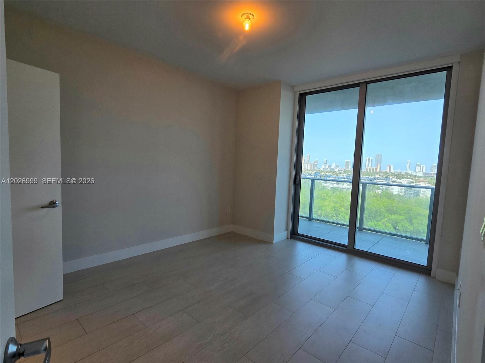 A bright bedroom with neutral finishes and light tile flooring offers a flexible layout with an ensuite bath nearby.
