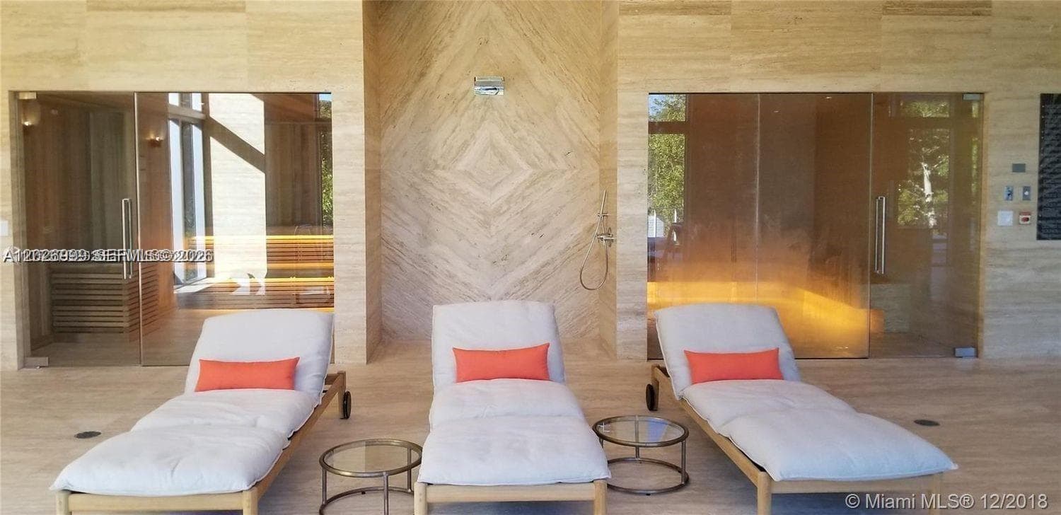 Warm wood built-ins, a linear fireplace, and contemporary seating create an inviting lounge area. Decorative wall accents and layered finishes give the space a refined, modern feel.
