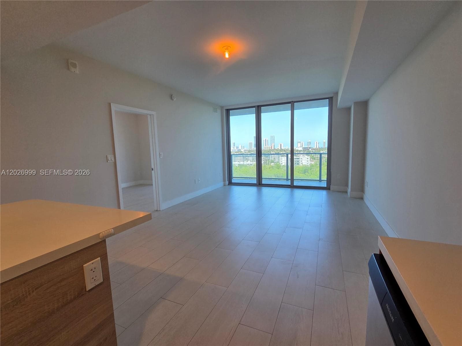 Floor-to-ceiling sliding glass doors bring natural light into the living area while showcasing treetop, water, and skyline views from the unit.