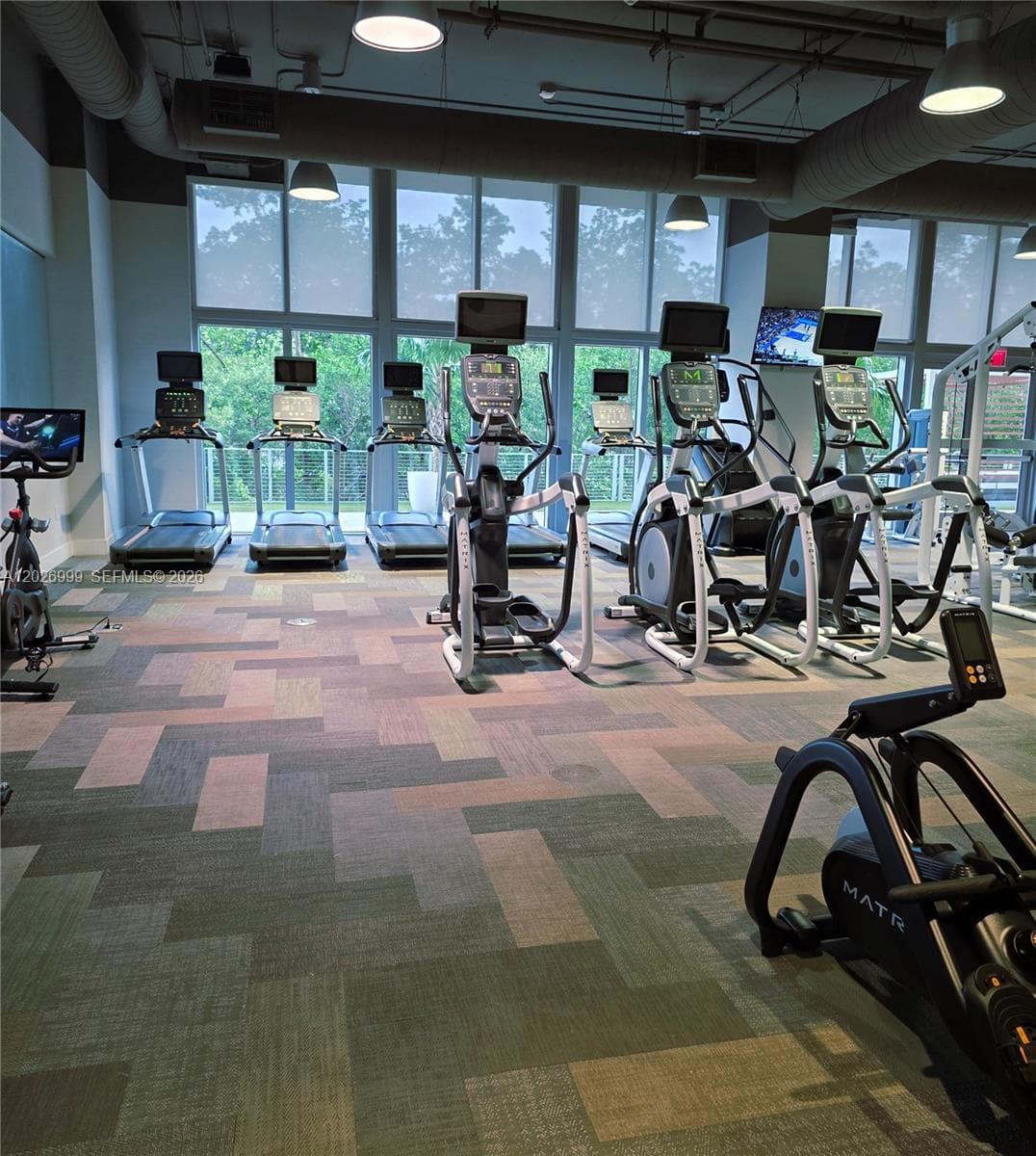 A row of professional-grade Matrix treadmills and a climbmill offer a high-performance workout experience with floor-to-ceiling window views.