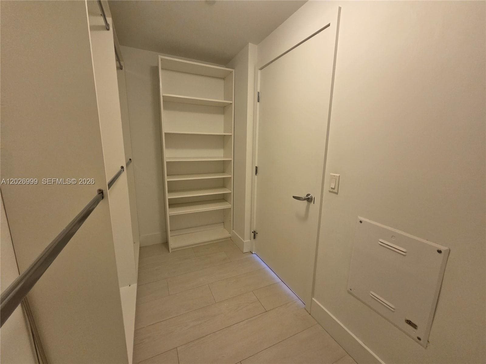 A bright interior hallway features light tile flooring, smooth wall finishes, and a streamlined layout connecting the home’s main spaces.