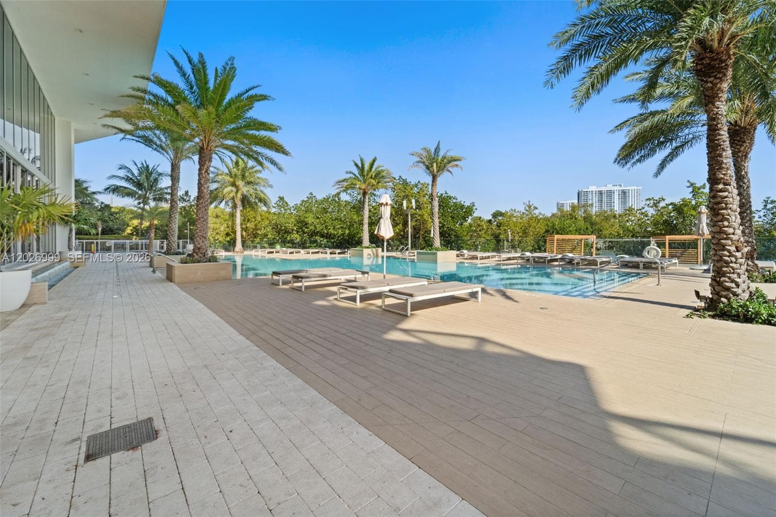 The indoor spa area features lounge chairs, warm stone finishes, and water features surrounded by floor-to-ceiling windows. Natural light and greenery views create a calm wellness environment.