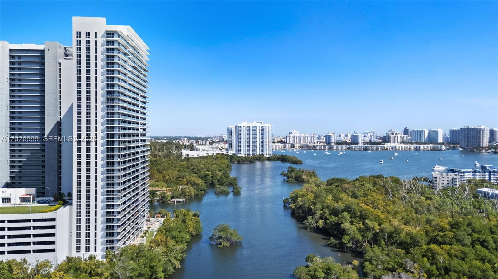 Expansive water and skyline views create a striking backdrop, with boats dotting the bay and lush greenery below.