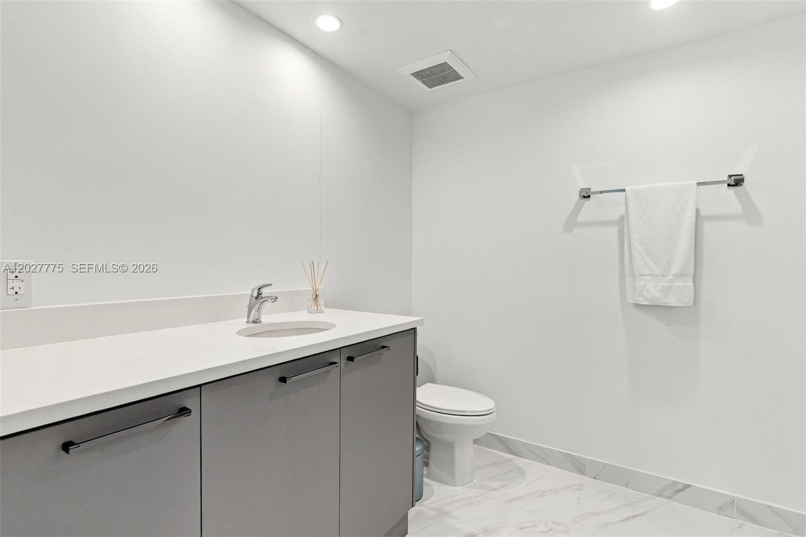 Recessed lighting, gray cabinetry, white countertop, undermount sink with chrome faucet, and white tile flooring