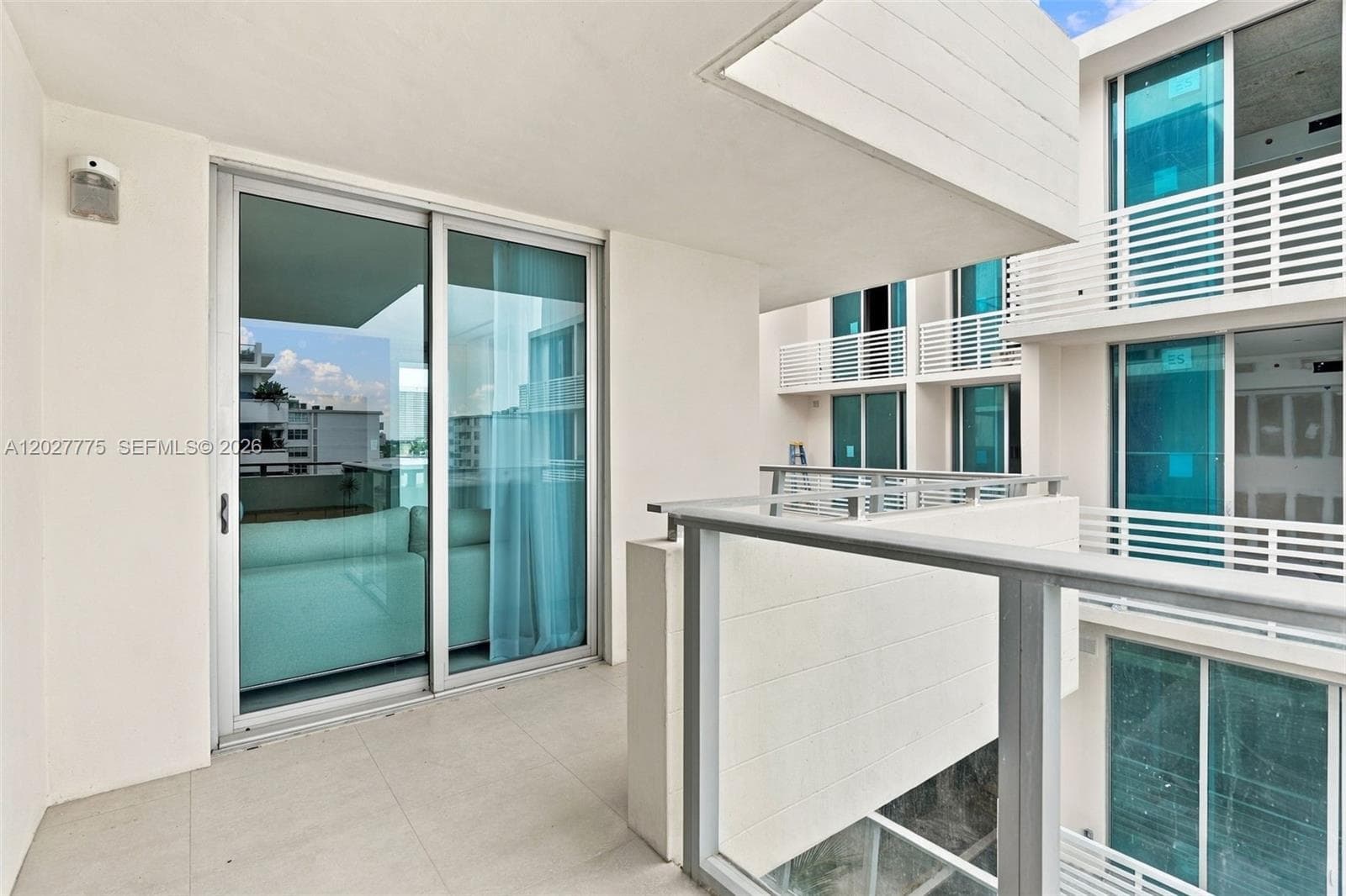 Balcony featuring light-toned tile flooring and a glass and metal railing system