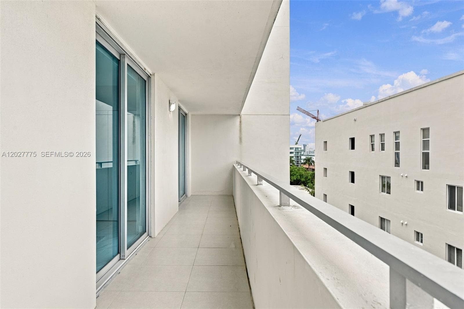 Balcony featuring a tiled floor, white railing, and sliding glass doors
