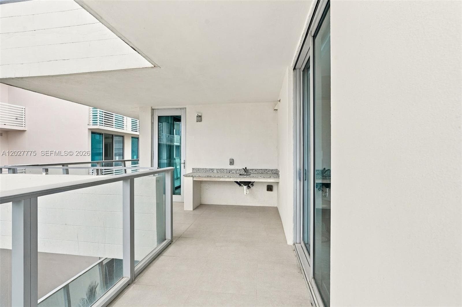 Outdoor balcony with glass panel railing and tile flooring