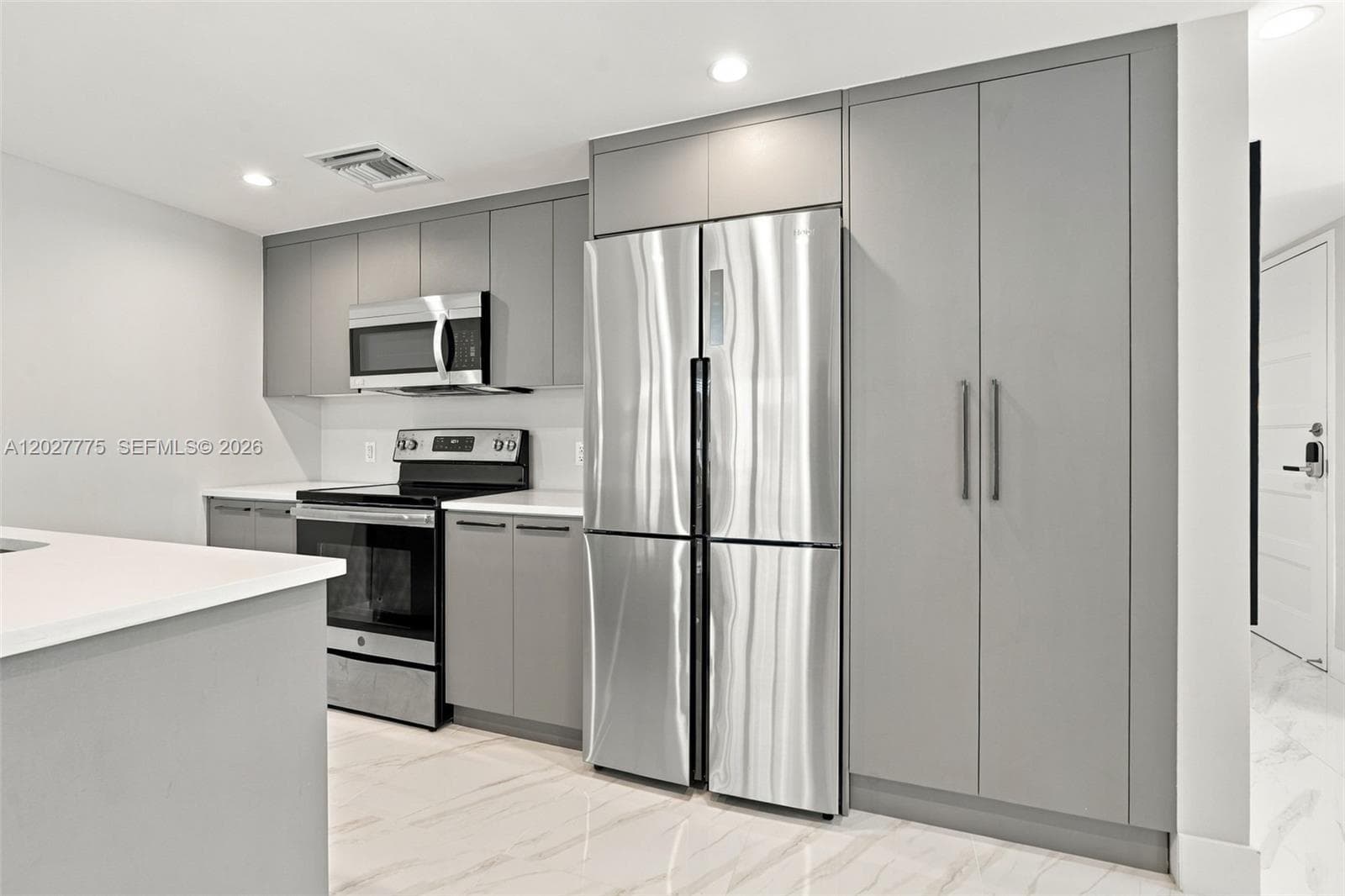 Kitchen featuring gray cabinetry, stainless steel appliances, a built-in microwave, white countertops, and recessed lighting